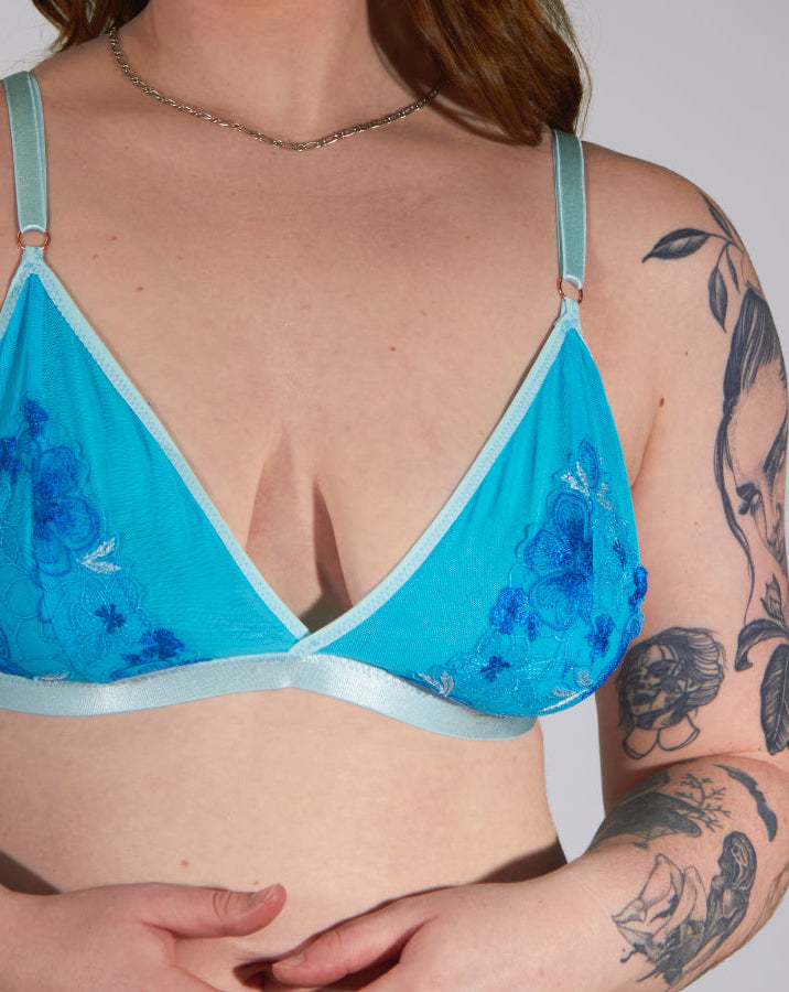 Person wearing a blue floral lingerie set against a plain background