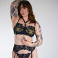 Woman wearing black lace lingerie against a plain background