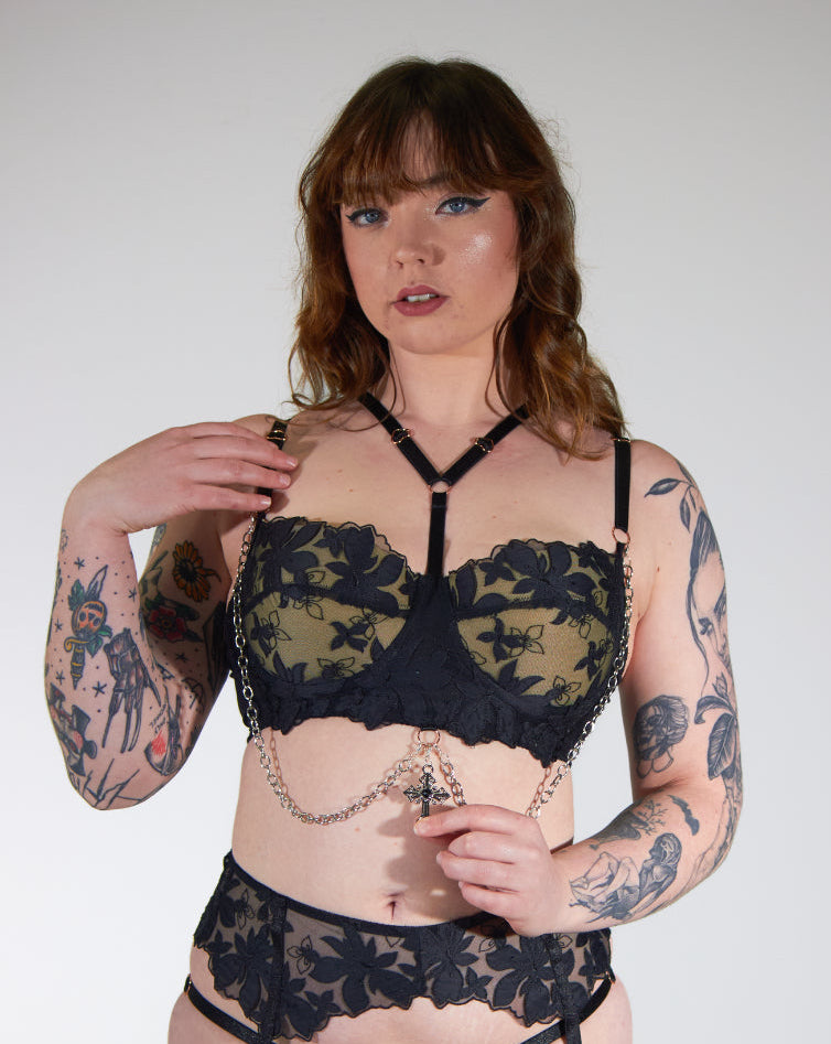 Woman wearing black lace lingerie against a plain background