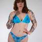 Woman wearing a blue lingerie with tattoos on her arms and legs against a white background