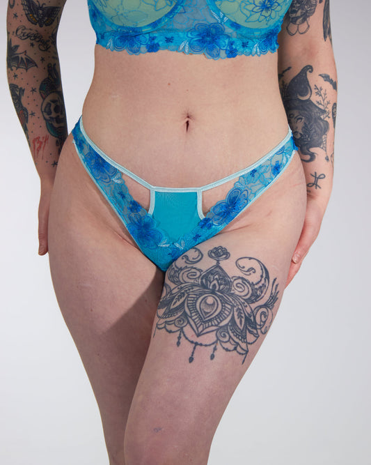 Person wearing blue lace underwear with a white background
