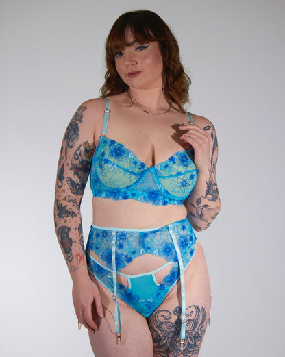 Woman wearing a blue patterned lingerie set against a plain background