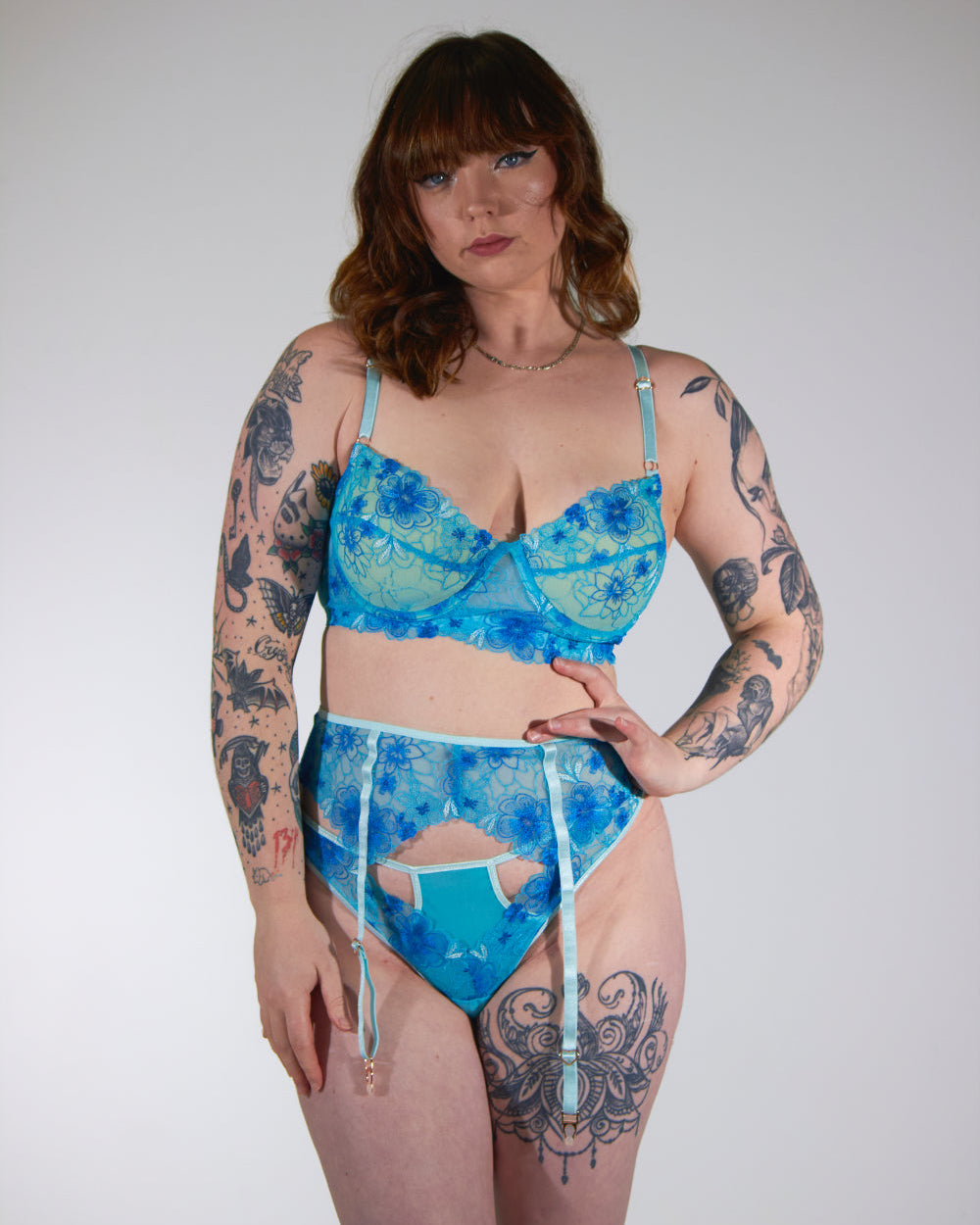 Woman wearing a blue floral lingerie set against a plain background