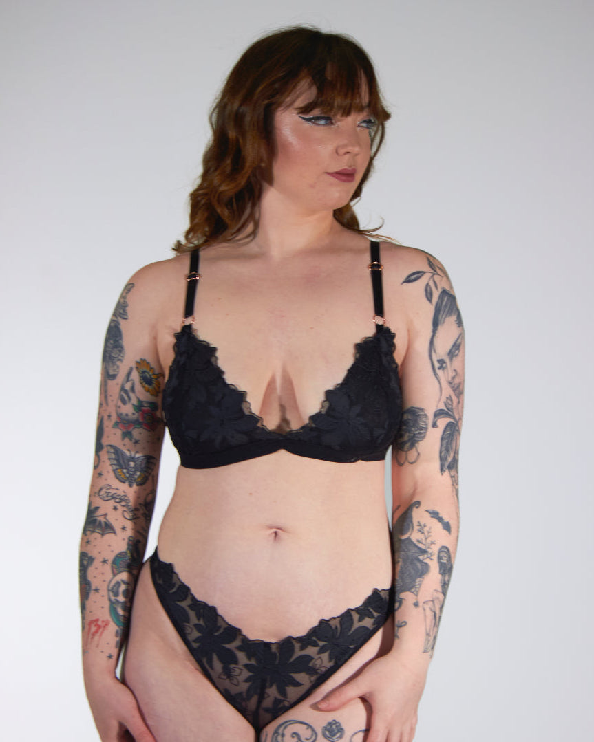 Woman wearing black lace lingerie against a plain background