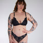 Woman wearing black lace lingerie against a plain background