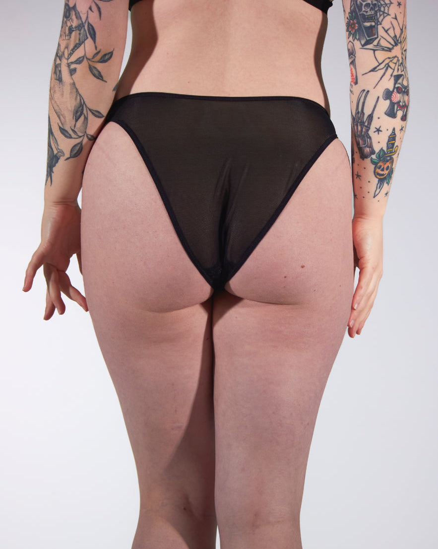 Person wearing sheer black stockings with a plain background