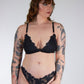 Woman wearing black lace lingerie against a plain background